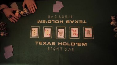 Erkek ve kadın elleri kumarhaneden masanın ortasına cips taşır ve onları iskambil kağıtlarıyla karıştırır. Yeşil masanın üzerinde. Yukarıdan görüntüle.