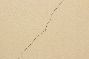 Çatlak ve soyulmuş eski bir bej duvar. Güç ve zaman kavramı