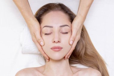 Kalın kaşlı genç kız ve beyaz arka planda mükemmel bir ten, güzellik fotoğrafı konsepti, cilt bakımı, spa konsepti, tedavi, yüz masajı.