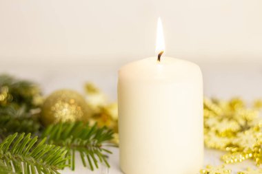 Yılbaşı ağacının arka planında yanan beyaz mum, altın toplar. Beyaz arka planda. Şenlik havası, Noel ayini.