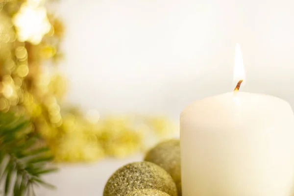 burning white candle on the background of the New Year Christmas tree, golden balls. on white background. festive mood, the sacrament of Christmas.