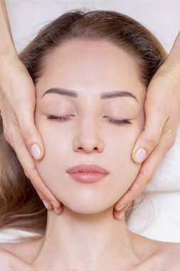 Kalın kaşlı genç kız ve beyaz arka planda mükemmel bir ten, güzellik fotoğrafı konsepti, cilt bakımı, spa konsepti, tedavi, yüz masajı.