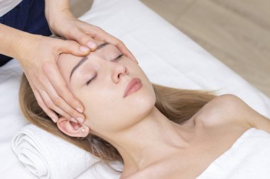 Genç bir kadın masaj salonundan zevk alıyor. Yüz masajı. Güzellik Salonu 'nda kaplıca masajı yaptıran genç bir kadın. Kaplıca ve vücut bakımı. Yüz güzelliği tedavisi. Kozmetoloji.. 