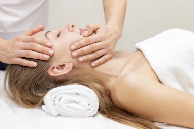 Genç bir kadın masaj salonundan zevk alıyor. Yüz masajı. Güzellik Salonu 'nda kaplıca masajı yaptıran genç bir kadın. Kaplıca ve vücut bakımı. Yüz güzelliği tedavisi. Kozmetoloji.. 