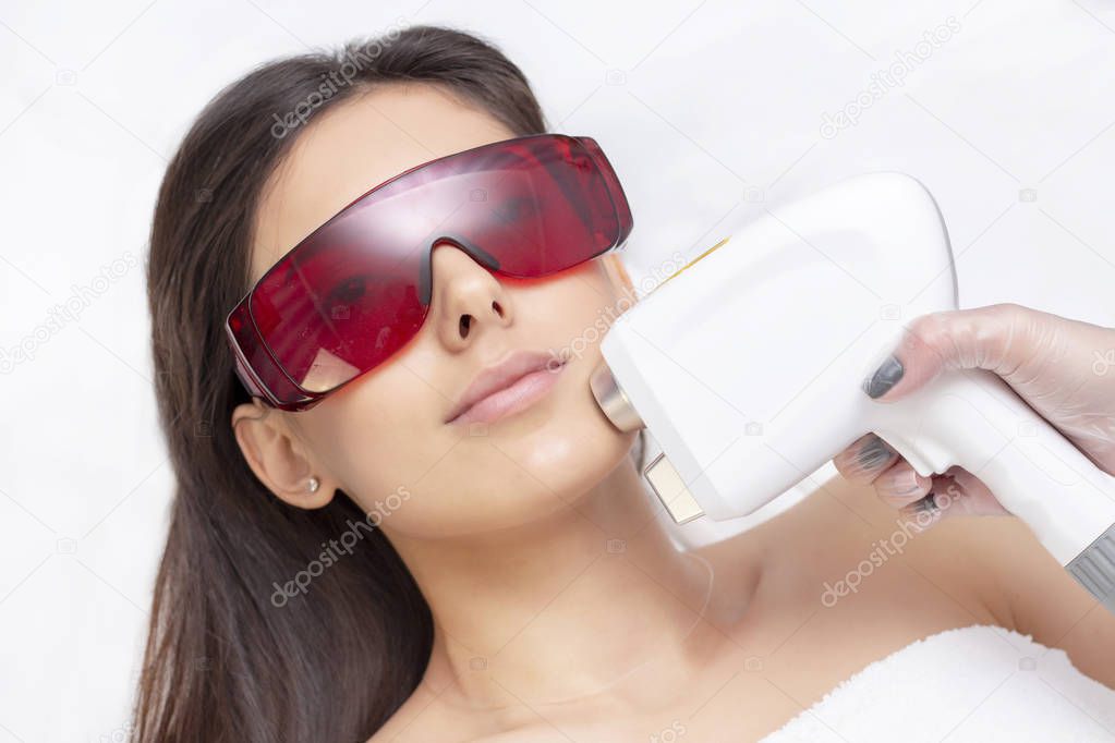procedure of photoepilation in the beauty salon. Young Woman Receiving Epilation Laser Treatment On Face At Beauty Center Close Up