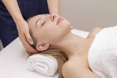 Genç bir kadın masaj salonundan zevk alıyor. Yüz masajı. Güzellik Salonu 'nda kaplıca masajı yaptıran genç bir kadın. Kaplıca ve vücut bakımı. Yüz güzelliği tedavisi. Kozmetoloji.. 