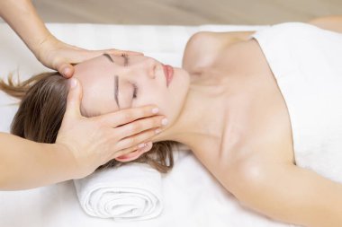 Genç bir kadın masaj salonundan zevk alıyor. Yüz masajı. Güzellik Salonu 'nda kaplıca masajı yaptıran genç bir kadın. Kaplıca ve vücut bakımı. Yüz güzelliği tedavisi. Kozmetoloji.. 