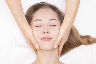 Genç bir kadın masaj salonundan zevk alıyor. Yüz masajı. Güzellik Salonu 'nda kaplıca masajı yaptıran genç bir kadın. Kaplıca ve vücut bakımı. Yüz güzelliği tedavisi. Kozmetoloji.. 