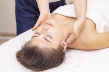 Servikal kaslara masaj ve gerdirme. Güzel bir kız spa salonunda masaj yaptırıyor. Açık tonlu fotoğraflar. Masaj ve sağlık konsepti. romatizma, artrosis
