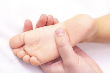 Küçük bir çocuğun ayağına masaj yapan bir masör. Anne bebek ayağına masaj yapıyor. Düz taban, gelişim, kas tonu ve displazinin önlenmesi.