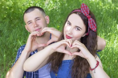 Mutlu romantik çift parmaklarıyla jest yapıyor. Ellerle kalp şekli oluşturan bir çift.