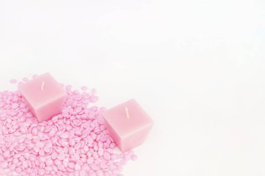 Beyaz arkaplanda mumlarla birlikte pembe rengin tüy dökmesi için arkaplan dokusu ağdası. Kopyalama alanı metniniz için boşluk. Tüy dökümü, ağda, tüysüz pürüzsüz cilt..