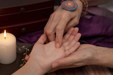 Cadı falcı kız elinden servet okuyor. Sihir konsepti, gelecek tahminleri, Noel zamanı. Mum ışığında koyu arkaplan