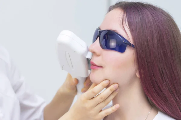 laser hair removal on the face, above the upper lip. removal of the antennae of the girl. girl on the depilation procedure.