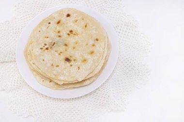 Hint chapati ekmeği. Beyaz arka planda beyaz bir tabakta chapati. Kuru bir tavada yemek yapmak.