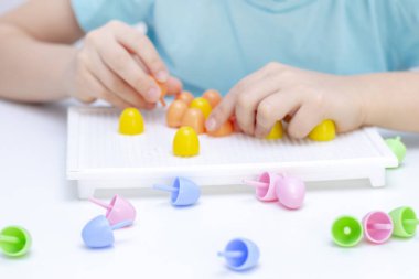 Çocuklarda iyi motor becerilerin gelişimi. Mozaiği topluyorum. Bir çocuğun elleri, yakın plan. Oyun yoluyla geliştirme. 