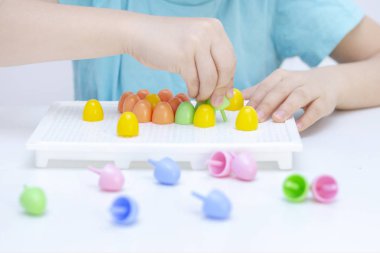 Çocuklarda iyi motor becerilerin gelişimi. Mozaiği topluyorum. Bir çocuğun elleri, yakın plan. Oyun yoluyla geliştirme. 