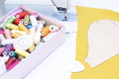 Dikiş stüdyosu. Dikiş makinesi. Dikiş işi için bir takım ögeler: iplikler, iğneler, iğneler, makas, mezura, vs..