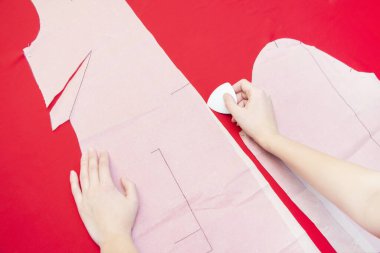 Dikiş Stüdyosu. Bir terzi bir kumaş parçasının etrafını sarmış. Elbise dikiyorum. Kırmızı bez.