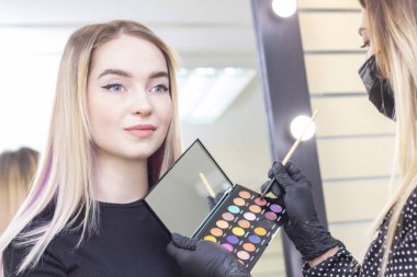 Makyaj sanatçısı kızların gözlerine makyaj yapar. Göz farı, palet. Güzellik salonu.. 