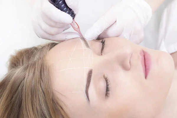 Close-up of a young woman undergoing permanent eyebrow makeup in a beauty salon