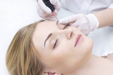 Makyaj malzemesi. Güzellik Uzmanı Elleri Kadın Yüzünde Kaş Dövmesi Yapıyor. Güzellik Salonunda Kalıcı Oral Makyaj. 