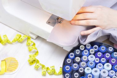 Arka plan dikişleri. Dikiş makinesindeki bir terzinin elleri. Stüdyo konsepti. İplikler, kumaşlar