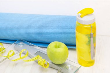Pul, yeşil elma, mezura, su şişesi ve tahta zeminde spor minderleri. kilo kaybı ve spor konsepti