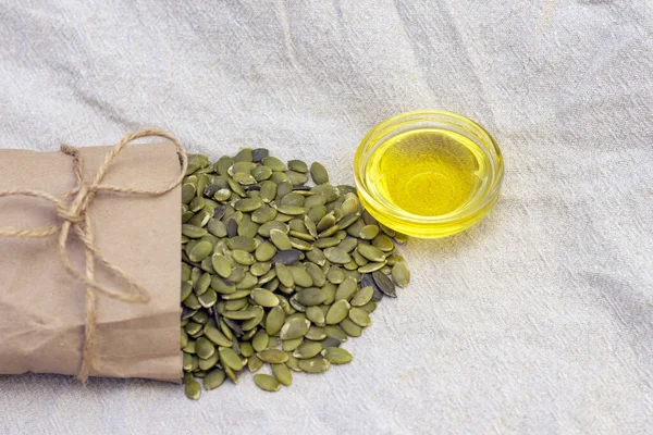 pumpkin seeds in a paper bag, pumpkin seed oil on natural linen. pumpkin seeds vitamins of group B and magnesium.