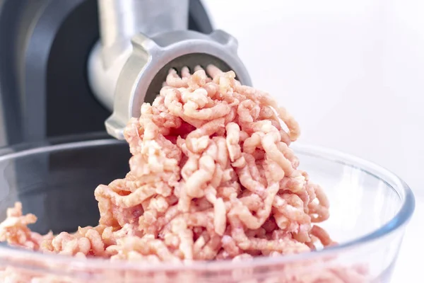Closeup of minced meat exiting from a grinder. Healthy homemade stuffing. on a light background
