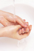Az ember kezet mos. kezek az antibakteriális szappan habjában. Baktériumok, koronavírusok elleni védelem. kézhigiénia. mosson kezet vízzel. Sok kéz. függőleges fénykép