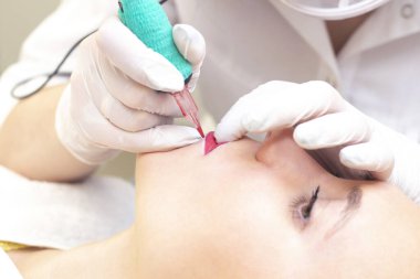 Güzellik salonunda dudaklarında kalıcı makyaj yapan genç bir kadın. Kalıcı Makyaj (Dövme)