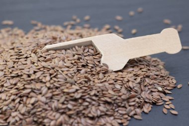 Siyah bir arka planda tahta bir kaşıkta keten ya da keten tohumu yığını. koyu arkaplan keten tohumu kavramı.