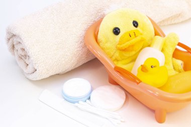 bebek hijyeni ve banyo malzemeleri, şampuan şişesi, bebek sabunu, havlu, sarı ördek lastik oyuncak, pamuk pedler ve tarak, tarak.