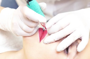 Güzellik salonunda dudaklarında kalıcı makyaj yapan genç bir kadın. Kalıcı Makyaj (Dövme)