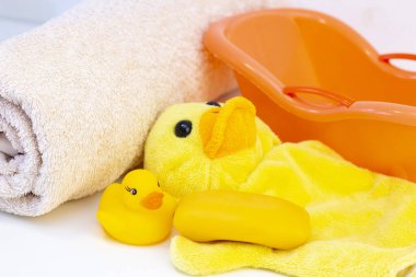 bebek hijyeni ve banyo malzemeleri, şampuan şişesi, bebek sabunu, havlu, sarı ördek lastik oyuncak, pamuk pedler ve tarak, tarak.