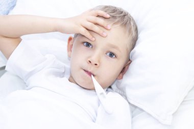 Oğlan ağzında termometreyle yatakta yatıyor. Sağlık sigortası konsepti ve hasta çocuk, koronavirüs, yüksek ateş,