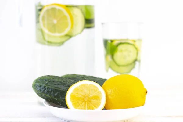 Health care, fitness, healthy eating concept. Fresh cool lemon cucumber drink with water, cocktail, detox drink, lemonade in a glass jug and a glass. cucumbers and lemon on a plate