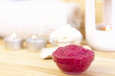 Şekerden yapılmış doğal pembe vücut fırçası. Mum ve şekerin arka planında cam bir fincanda pembe fırça..