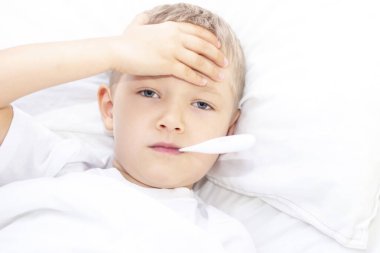 Oğlan ağzında termometreyle yatakta yatıyor. Sağlık sigortası konsepti ve hasta çocuk, koronavirüs, yüksek ateş,