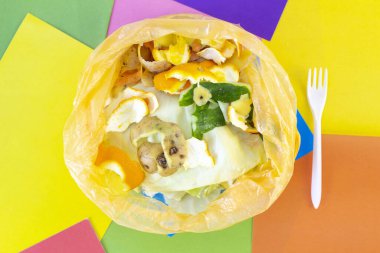 Çöp, plastik poşetteki yiyecek atıkları, renkli ve soyut bir arkaplanda. Dünya gezegeninin ekolojisi ve kirliliği. Çöpleri ayıklıyorum. Plastik çatal