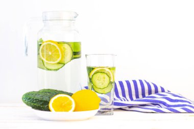 Sağlık hizmeti, fitness, sağlıklı beslenme konsepti. Taze soğuk limon salatalığı suyu, kokteyl, detoks içeceği, bardakta limonata ve bardakta. Bir tabakta salatalık ve limon