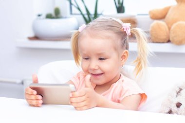 Mutlu kız cep telefonu kullanıyor, video görüşmeleri için akıllı telefon kullanıyor, akrabalarla konuşuyor, evde oturan bir kız, online bilgisayar webcam, video görüşmesi yapıyor..