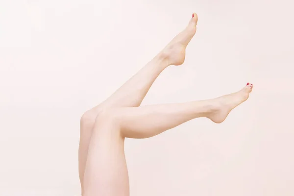Γυναίκα Γυμνά Πόδια Αυξήσει Ένα Μπεζ Φόντο Σαλόνι Ομορφιάς Αποτρίχωση — Φωτογραφία Αρχείου