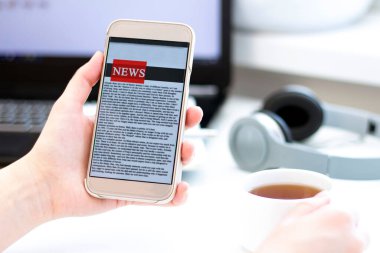 Bir cep telefonundan internet haberleri. Akıllı telefon ekran uygulamasında haber ya da makale okuyan iş kadınlarını kapatın. El ele tutuşan akıllı cihaz. Model web sitesi. Gazete.