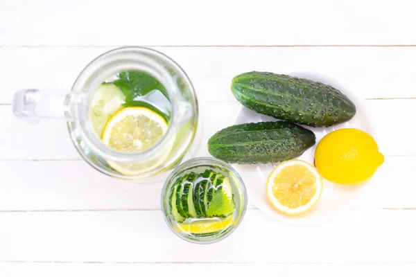 Health care, fitness, healthy eating concept. Fresh cool lemon cucumber drink with water, cocktail, detox drink, lemonade in a glass jug and a glass. cucumbers and lemon on a plate