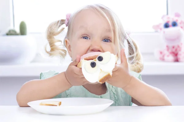 Child Girl Blonde Eats Sandwich Table Light Background — Stock Photo, Image