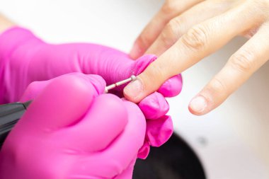 Sıkı giyin manikür. Pembe eldivenli manikürcü bir kız..