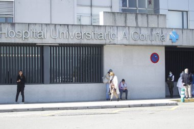 Coruna-İspanya. Yaşlı kişi 14 Mart 2020 'de kovid-19 Coronavirus için koltuk değneği ve yüz maskesi ile hastaneden ayrılıyor..