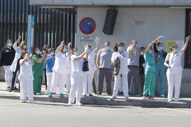 Bir Coruna-İspanya. Yeni koronavirüs kriziyle ilgilenen sağlık çalışanları, 26 Mart 2020 'de Sivil Muhafızlar ve diğer güvenlik güçleri tarafından hastanenin önünde alkışlanırken, buna karşılık alkış tutuyorlar.